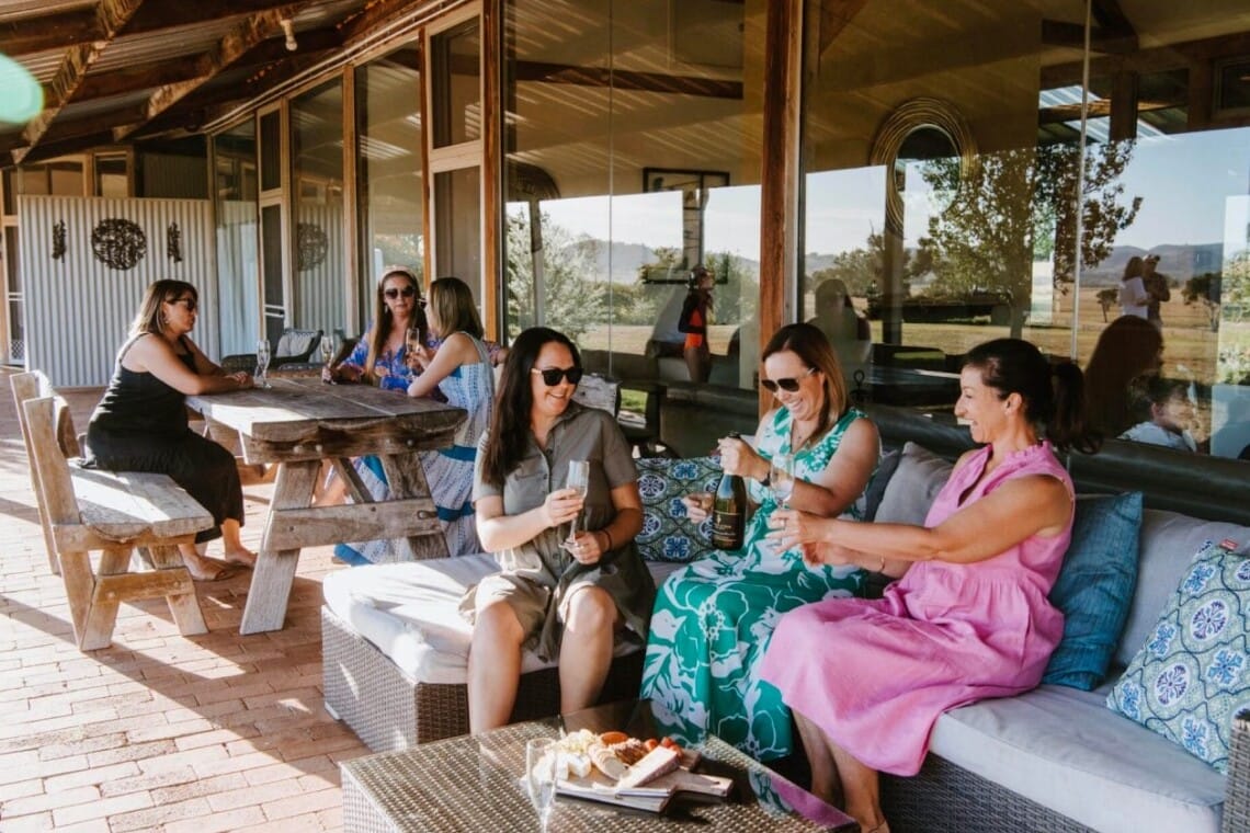 Group of women enjoying wine and laughter at Owl Head Lodge Gulgong, a stylish country accommodation listed with Travellarks Getaways.